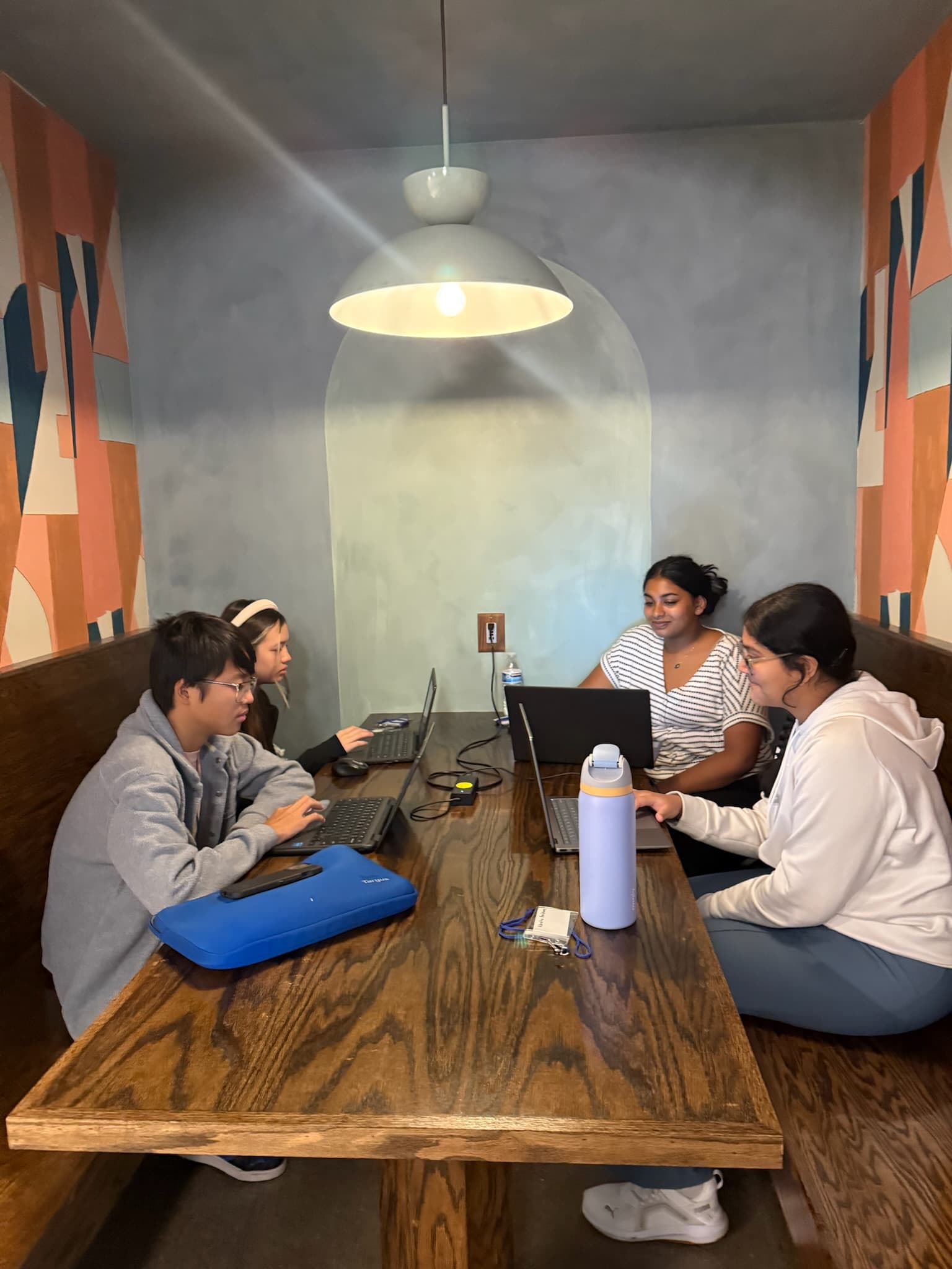 Four Hack the Track students coding together in a booth
